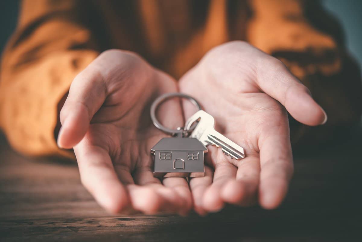 Sleutel in deur met huisvormige sleutelhanger.